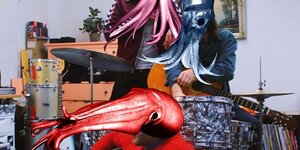 Musiker, die Kraken-Masken über ihren Köpfen tragen.