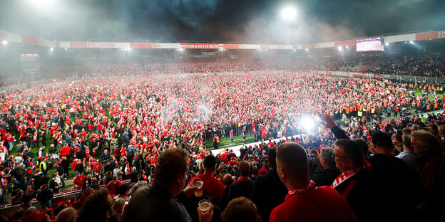 Menschen in roter Kleidung stehen in einem Stadion
