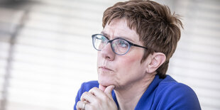 Eine Frau stützt ihren Kopf auf ihre ineinandergefalteten Hände. Es ist Annegret Kramp-Karrenbauer