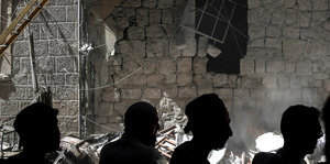 Ariha: Menschen stehen vor einem Gebäude, das bei einem Luftangriff durch die syrischen Regierungskräfte beschädigt wurde