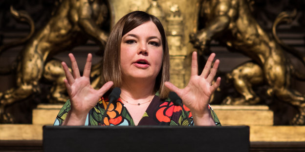 Katharina Fegebank hält eine Rede vor einem goldenen Wappen. Katharina Fegebank hält eine Rede vor einem goldenen Wappen.