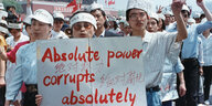 Protestierende auf dem Tienanmen-Platz. Sie tragen ein Transparent vor sich her, auf dem steht: Absolute power corrupts absolutely