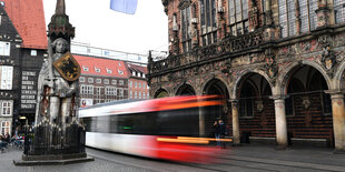 Eine Strassenbahn fährt zwischen dem Bremer Roland und dem Rathaus entlang.