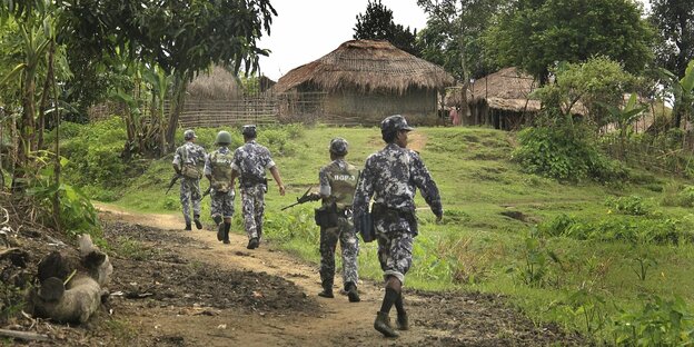 Mehrere Soldaten patrouillieren vor einem Dorf aus Hütten