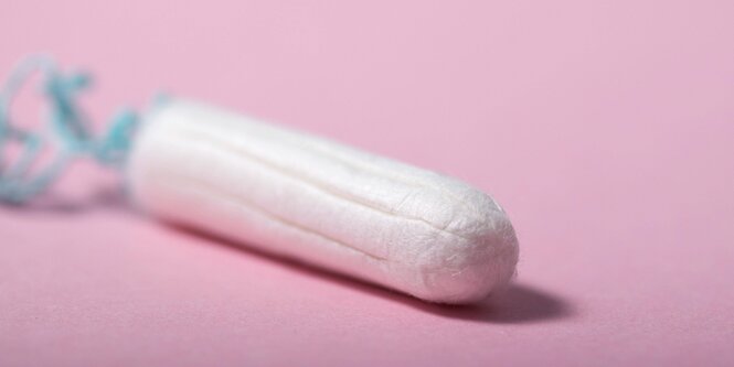 Ein Tampon liegt auf einem rosa Untergrund