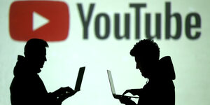 Silhouetten von zwei Personen, die sich vor einem Logo von Youtube gegenüber sitzen