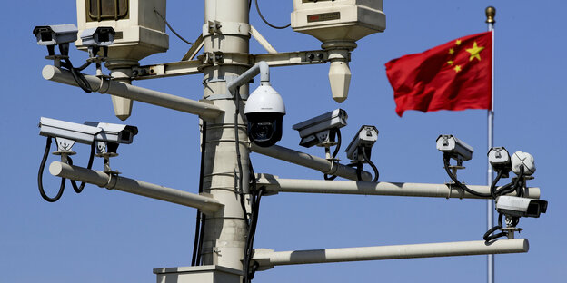 Ein Mast mit mehren Überwachungskameras vor einer chinesischen Flagge