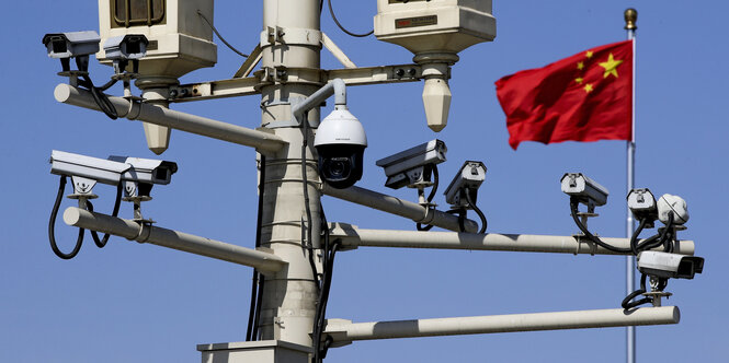 Ein Mast mit mehren Überwachungskameras vor einer chinesischen Flagge