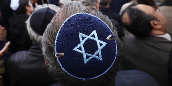 Ein Mann mit grauen Haaren trägt eine blaue Kippa