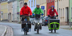 Drei elektrische Lastenfahrräder fahren nebeneinander