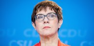 CDU-Chefin Kramp-Karrenbauer steht vor einer blauen Wand und guckt nachdenklich