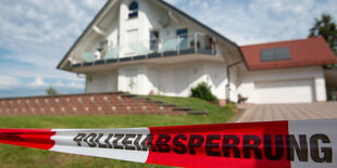 Das Einfamilienhaus von Walter Lübcke ist im Hintergrund zu sehen. Davor ein Vorgarten mit grünem Rasen. Im Vordergrund ein rotweißes Absperrband mit der Aufschrift "Polizeiabsperrung".