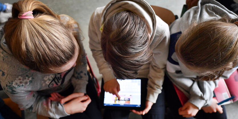 Drei Mädchen über ein Tablet gebeugt