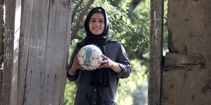 Eine lächelnde Frau hält einen Fußball