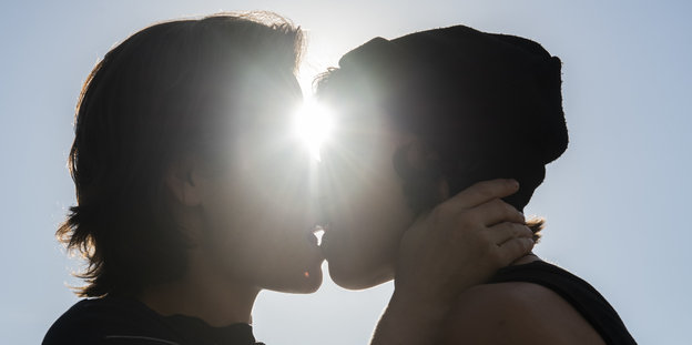 Zwei Frauen küssen sich im Gegenlicht der Sonne