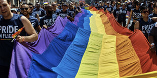 Viele Menschen tragen eine riesige Regenbogenflagge