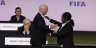 Gianni Infantino umarmt Fatma Samoura, dahinter ist das Logo der FIFA zu sehen
