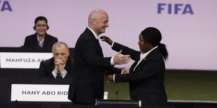 Gianni Infantino umarmt Fatma Samoura, dahinter ist das Logo der FIFA zu sehen