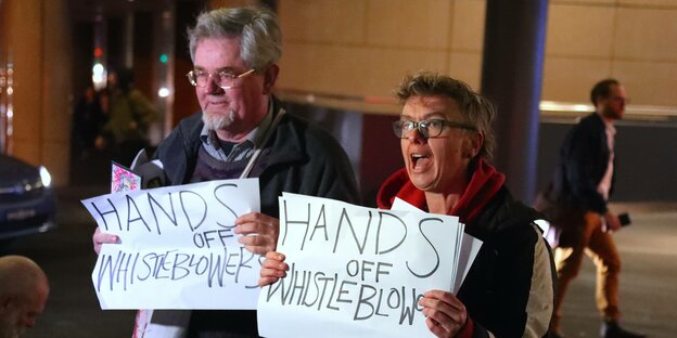 Zwei Demonstranten halten Schilder mit der Aufschrift "Hands off Whistleblowers" hoch