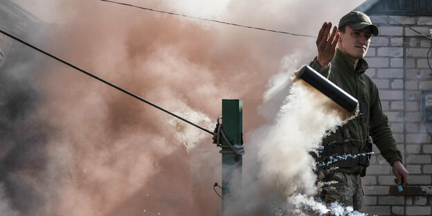 Ein Mann zündet eine Rauchbombe, um Drohnen abzuwehren