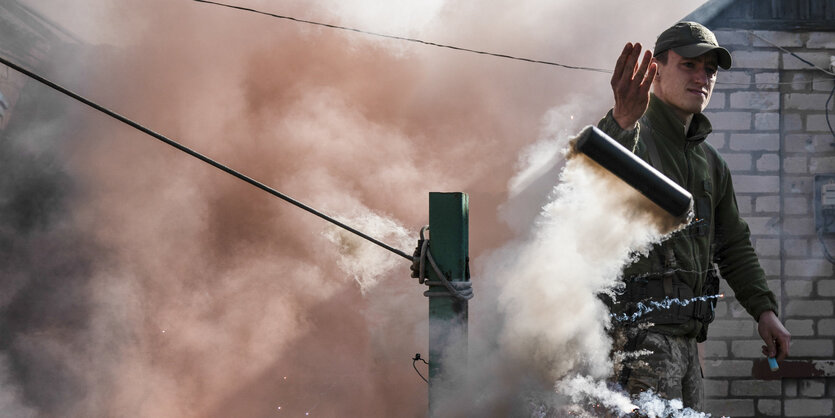 Ein Mann zündet eine Rauchbombe, um Drohnen abzuwehren