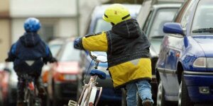 Zwei kleine Kinder sind mit ihrem Fahrrad auf der Straße unterwegs