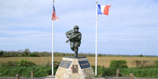 Ein Denkmal, daneben stehne US- und französische Flagge Ein Denkmal, daneben stehne US- und französische Flagge
