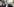 Deniz Yücel steht vor dem Berliner Amtsgericht Tiergarten, er trägt ein weißes Hemd und ein Sakko und zeigt mit dem Finder aus dem Bild.