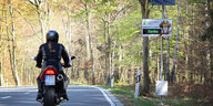 Ein Motorrad fährt in der Eifel an einer Geschwindigkeitsanzeige vorbei.