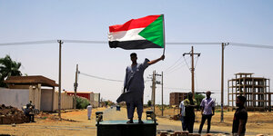 Mann schwingt sudanesische Flagge