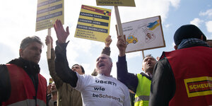 Protestierende Taxifahrende halten Schilder gegen die Verkehrpolitik von Andreas Scheuer in den Berliner Himmel