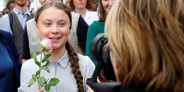 Greta Thunberg hält eine Rose und wird fotografiert