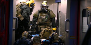 SEK-Beamten mit Atemschutzmasken und Schutzanzügen steigen während der Stürmung der Wohnung von Sief Allah H. in einen Krankenwagen