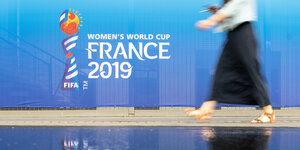 Eine Frau geht an einem Banner für die Fußball-Weltmeisterschaft der Frauen vorbei