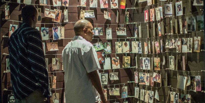 Zwei Männer stehen vor einer Wand mit Fotos