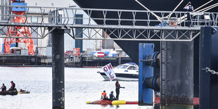 Ein Schiff im Hafen. davor Menschen auf einem Boot