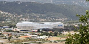 Ein Fußballstadion aus der Ferne fotografiert, dahinter Berge