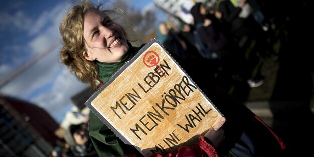 Eine Frau hält ein Plakat mit der Aufschrift "Mein Leben, mein Körper, meine Wahl"