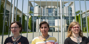 Drei Aktivistinnen sind am Hals an den Zaun des Kanzleramtes in Berlin gekettet