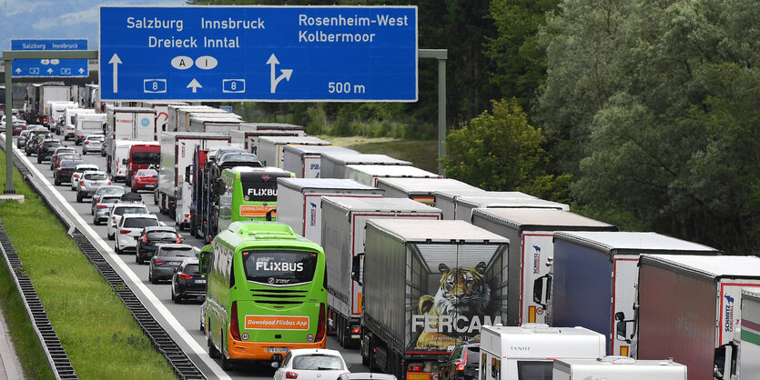 Auf einer überfüllten Autobahn steht ein grüner Bus des Fernreisenanbieters Flixbus neben Lastern