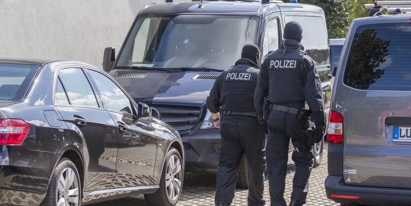 Polizisten einer Spezialeinheint laufen auf Autos zu