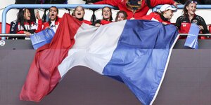 Frauen auf einer Fußball-Tribüne halten die französische Flagge