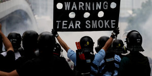 Polizisten in Hongkong mit Schild "Warning Tear Smoke"