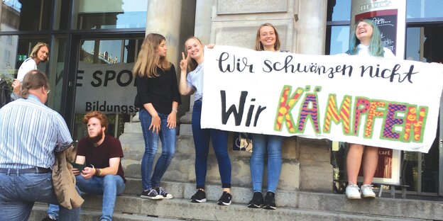 Drei Schülerinnen halten ein Plakat mit der Aufschrift: "Wir scwänzen nicht, wir kämpfen".