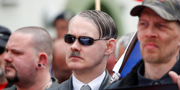 Drei Nazi-Gesichter, das in der Mitte mit Sonnenbrille auf der Nase und Hitlerschnauzbart