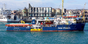 Die Sea-Watch 3 in einem italienischen Hafen, daneben ein Containerschiff