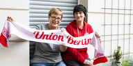 Sabine Landsberger und Silvia Trompeteler halten einen Union-Berlin-Schal hoch