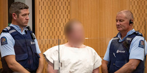 Der mutmaßliche Attentäter von Christchurch zwischen zwei Polizisten im Gerichtssaal