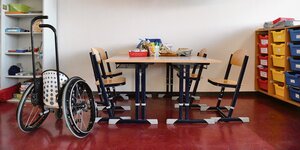 Ein Klassenzimmer mit Stühlen und einem Rollstuhl.