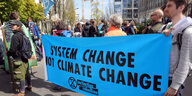 Junge Menschen halten ein Transparent auf dem steht: "System change not climate change"
